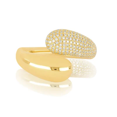 The Diamond & Gold Jumbo Double Dome Ring features one smooth, polished gold dome and another encrusted with rows of sparkling diamonds, displayed on a reflective white surface.